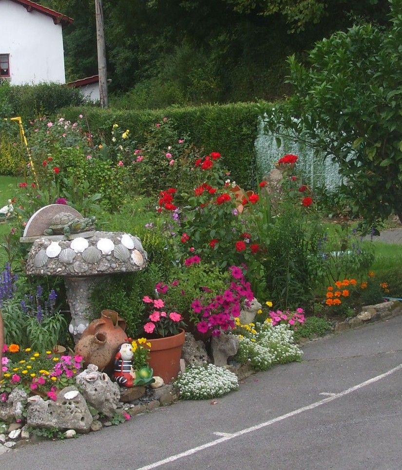 Fuente de piedra con tortuga decorativa en un jardín lleno de flores y macetas